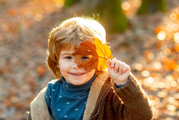 Niños de otoño, niño encantador jugando en el parque de otoño.