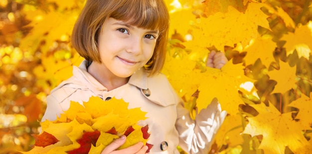 Niños en el parque con hojas de otoño. Enfoque selectivo.