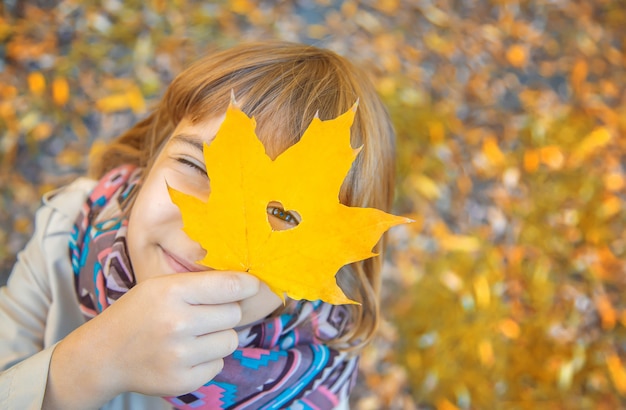 Niños en el parque con hojas de otoño. Enfoque selectivo.