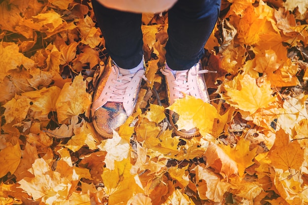 Niños en el parque con hojas de otoño en los zapatos Enfoque selectivo