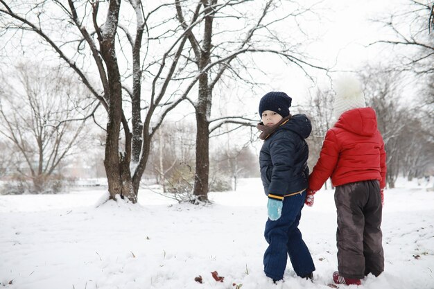 Los niños en el parque de invierno juegan con nieve.