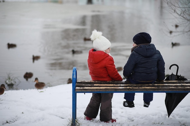 Los niños en el parque de invierno juegan con nieve.