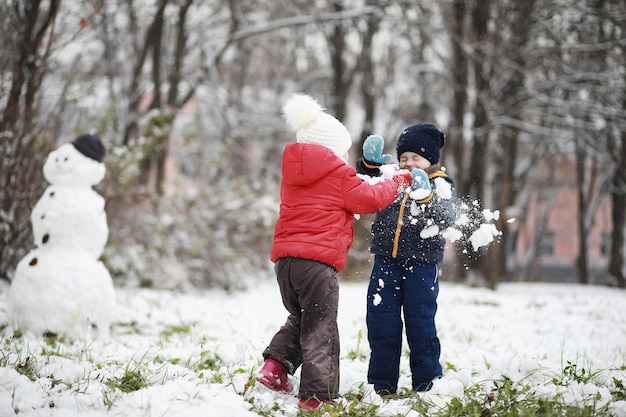 Los niños en el parque de invierno juegan con nieve.