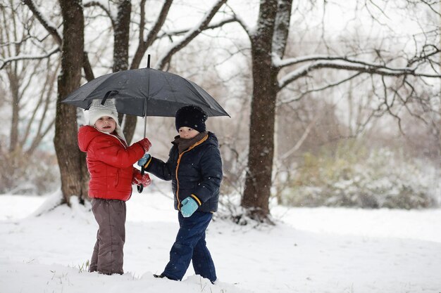 Los niños en el parque de invierno juegan con nieve.