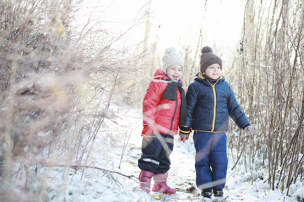 Los niños en el parque de invierno juegan con nieve.