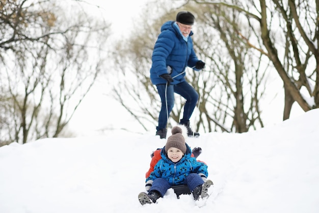 Niños en el parque en invierno. Los niños juegan con nieve en el patio de recreo. Esculpen muñecos de nieve y se deslizan por las colinas.