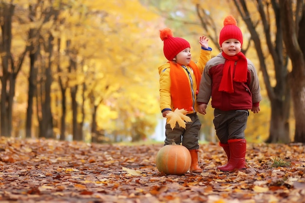 Niños en el parque de otoño con calabaza