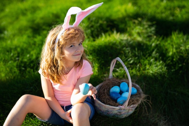 Niños de pascua niños felices de pascua en orejas de conejo con huevo de pascua en canasta niño juega en huevos de caza