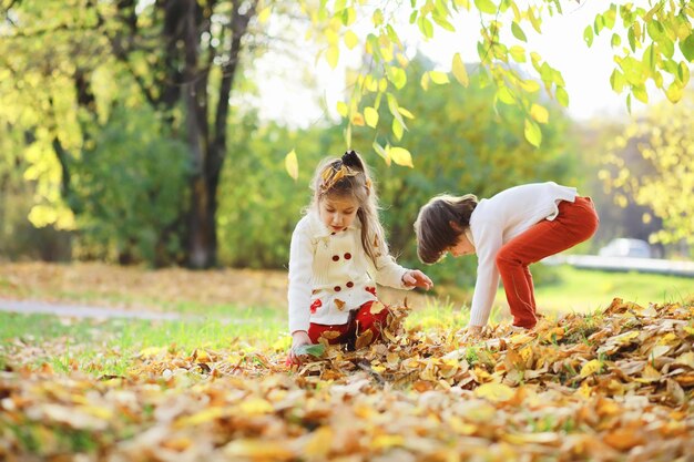 Foto niños a pasear por el parque de otoño. caída de hojas en el parque. familia. otoño. felicidad.