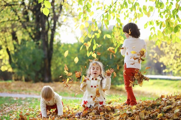 Niños a pasear por el parque de otoño. Caída de hojas en el parque. Familia. Otoño. Felicidad.