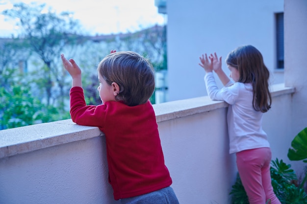 Niños pequeños aplaudiendo desde el balcón