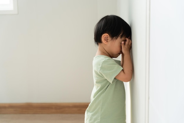 niños pequeños asiáticos niña cubriendo los ojos con las manos jugando a las escondidas de pie junto a una casa de pared niño adorable divirtiéndose en el hogar familia feliz divirtiéndose con la actividad de los niños