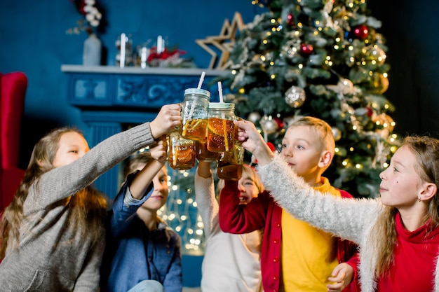 Los niños pequeños beben limonada y se cuentan historias navideñas y se ríen.
