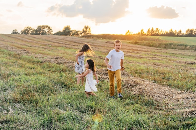 Foto los niños pequeños corren hacia adelante a través del campo dando la vuelta los niños despreocupados juegan juntos en el prado cubierto de hierba caminar al aire libre