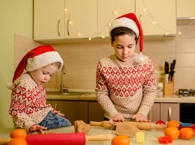 Los niños pequeños divertidos hornean panes de jengibre festivos caseros. Repostería casera