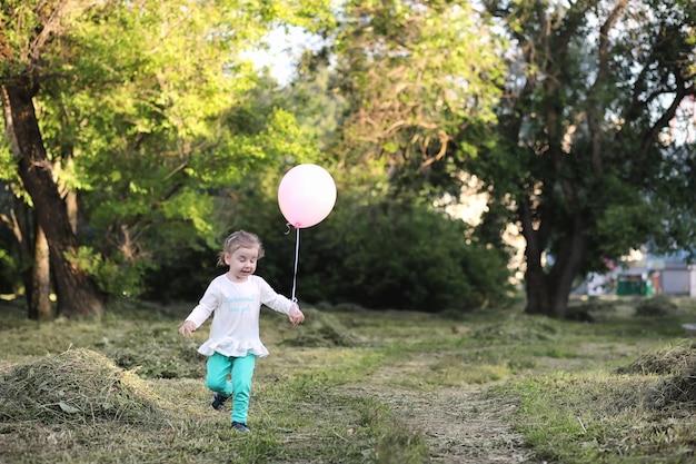 Los niños pequeños están caminando en un parque con globos