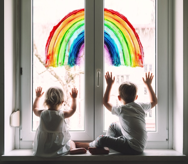 niños pequeños en el fondo de la pintura arco iris en la ventana apoyo visual positivo