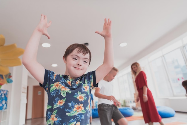 Niños pequeños de la guardería con una maestra en el suelo en el interior del aula haciendo ejercicio Saltando sobre la pista de círculos de hula hoop en el suelo