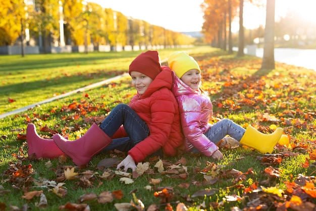 Niños pequeños hermano y hermana con botas de goma y ropa brillante en el parque de otoño