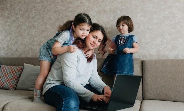 Los niños pequeños impiden que su madre trabaje en la computadora. trabajo remoto en casa