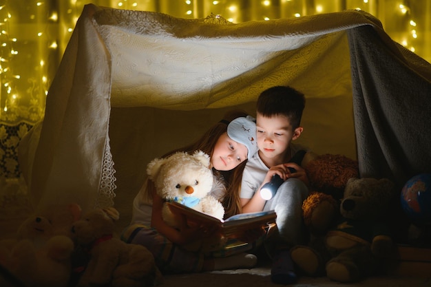 Niños pequeños leyendo cuentos antes de dormir en casa
