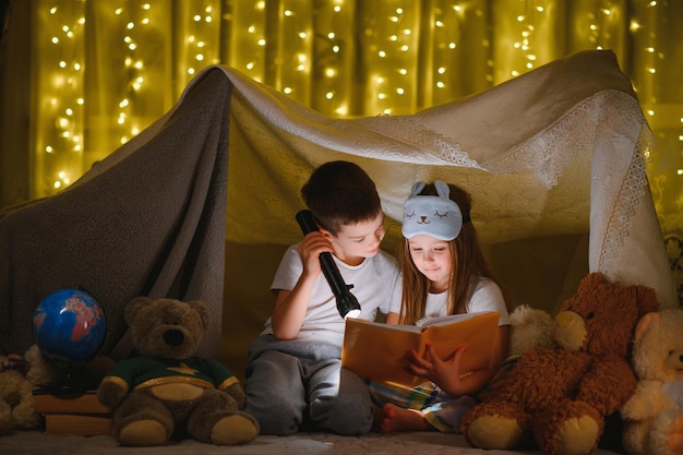 Niños pequeños leyendo cuentos antes de dormir en casa