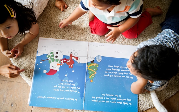 Niños pequeños leyendo juntos una historia navideña