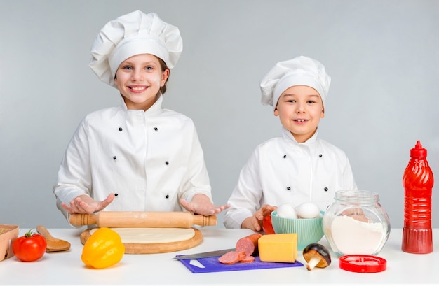 Niños pequeños en una mesa haciendo pizza