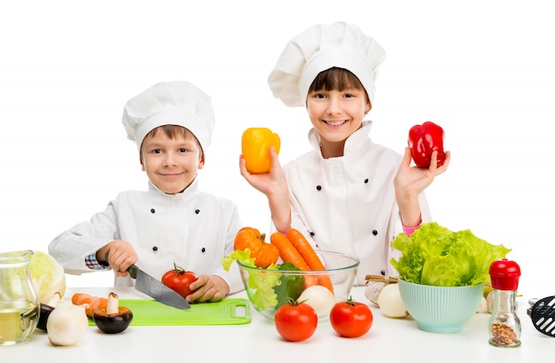 Niños pequeños en una mesa con verduras