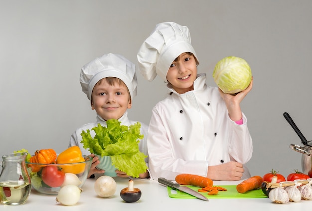 Niños pequeños en una mesa con verduras