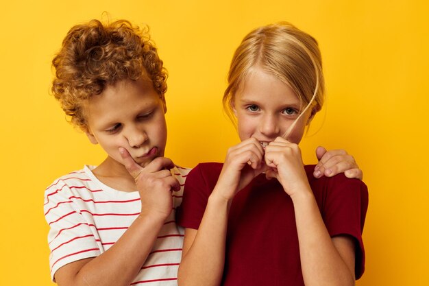 Niños pequeños de pie uno al lado del otro posando emociones infantiles sobre fondo de color