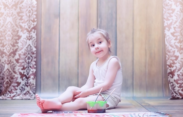 Los niños pequeños pintan en una hoja grande de papel