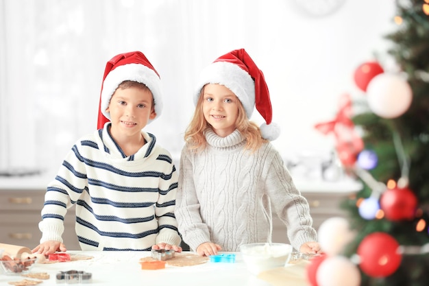 Los niños pequeños preparando galletas de Navidad en la cocina