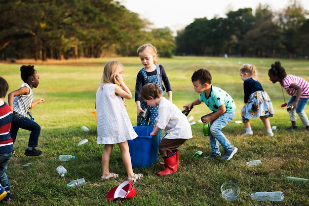 Niños pequeños que separan las botellas de reciclaje a la papelera