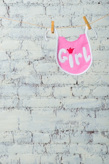 Foto niños pequeños saliva rosa en una cuerda sobre un fondo de pared de ladrillo blanco