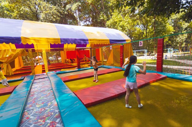 Los niños pequeños saltan en el brillante parque de trampolines al aire libre en el parque de verano