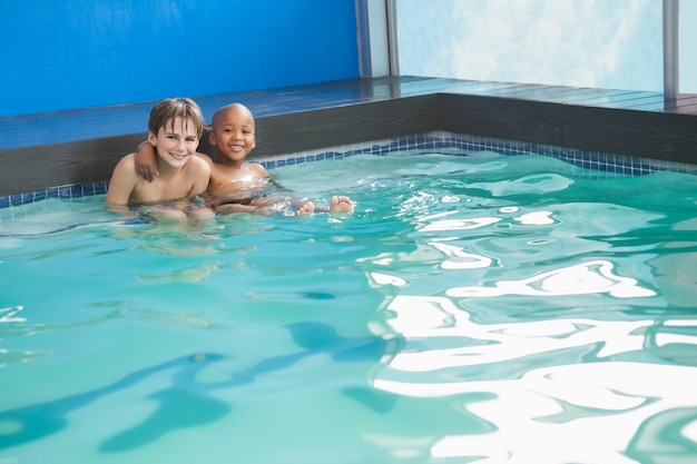 Niños pequeños sentados en la piscina