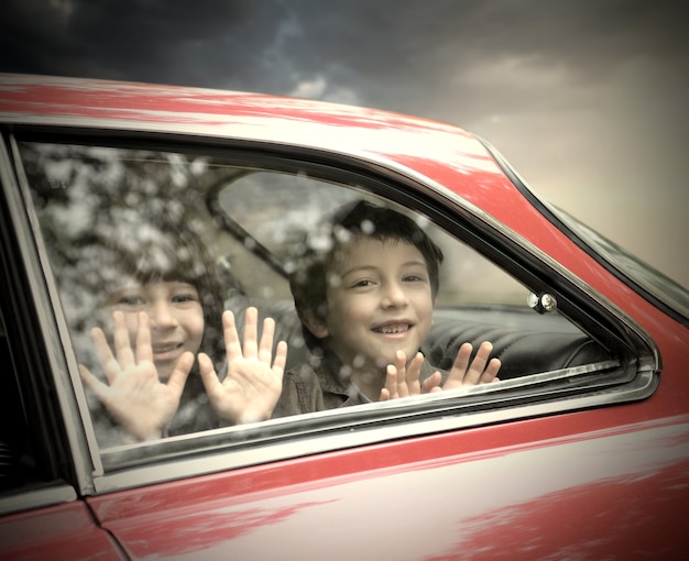 Niños pequeños sonriendo desde un coche