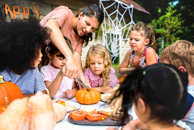 Niños pequeños tallando Halloween jack-o-lanterns