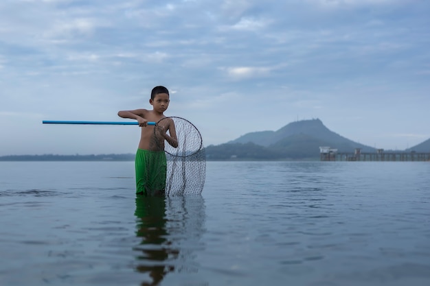 Los niños pescadores todavía echaban aldeas de pescadores. Pesca de natación y equipos de pesca. felices las sonrisas de los niños. Los pescadores lanzarán En el viejo bote de madera Un hermoso amanecer por la mañana.