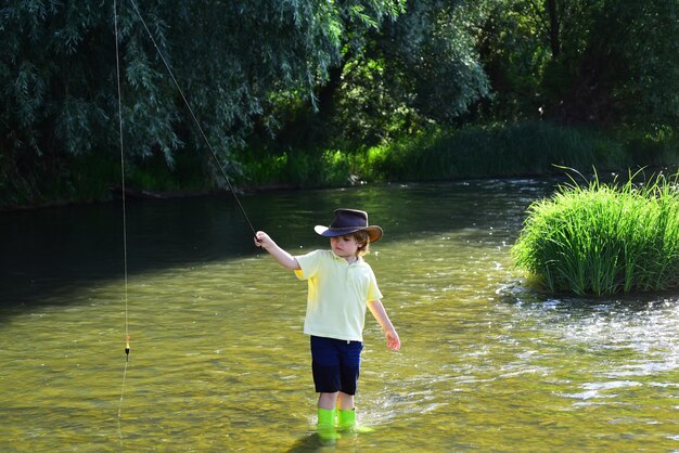 Niños pescando un niño pequeño tirando de una caña de pescar mientras pesca el fin de semana Pescador con sombrero Un niño lindo es