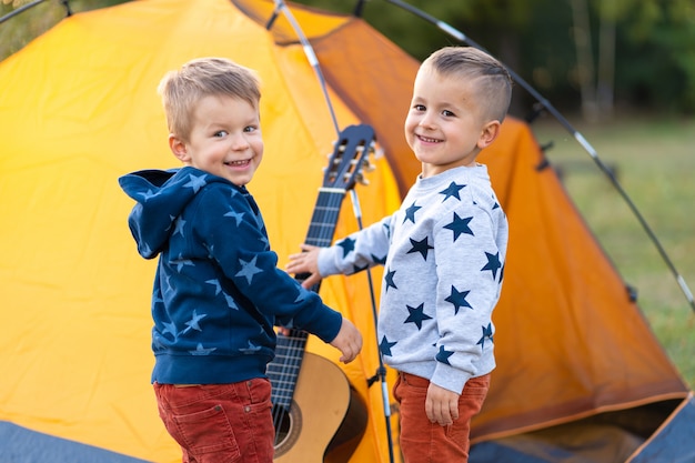 Los niños le piden a papá que toque la guitarra. Camping con familia en el bosque. Feliz fin de semana familiar