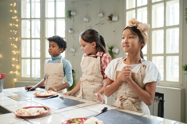 Niños de pie en la lección de cocina.