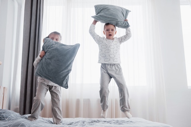 Niños en pijama suave y cálido jugando en la cama