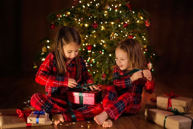 Niños en pijamas a cuadros están desempacando regalos de Navidad