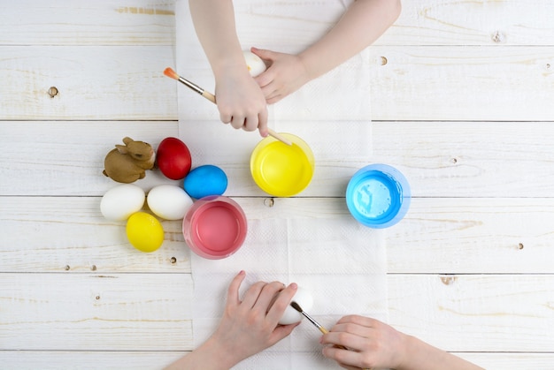 Los niños pintan huevos de Pascua en la mesa de madera