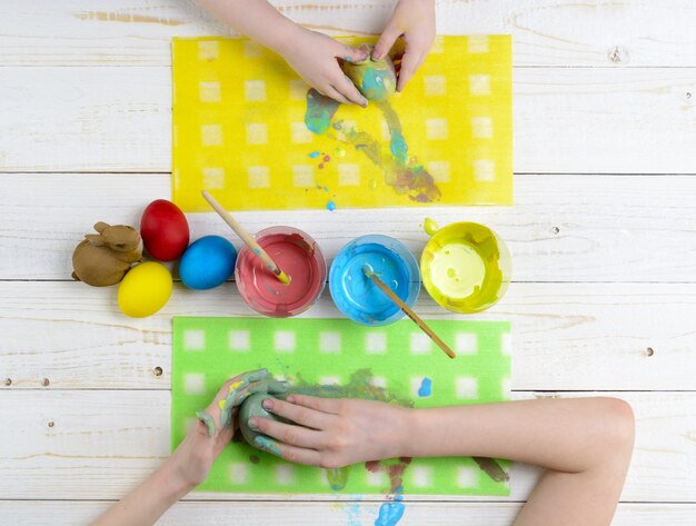 Los niños pintan huevos de Pascua en la mesa de madera