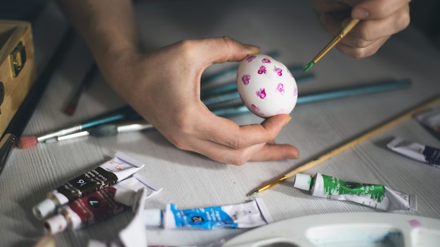 los niños pintan huevos de pascua en una mesa con materiales de arte