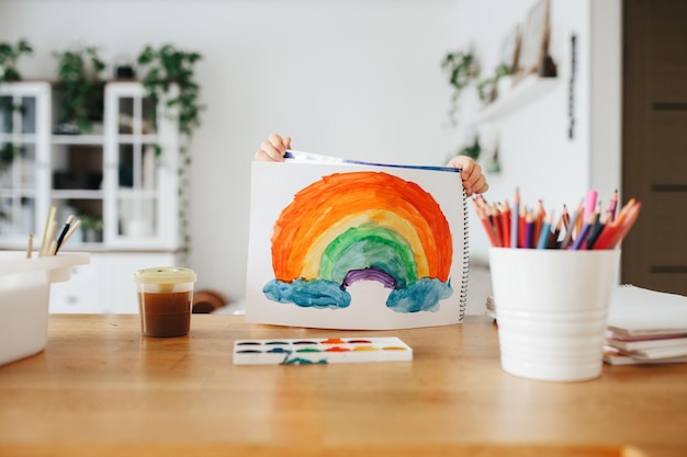 Niños pintando arcoíris de acuarela en la mesa en casa