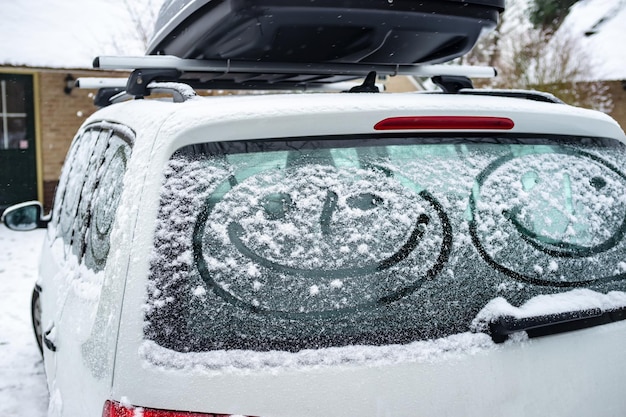 Foto los niños pintaron una cara sonriente en las ventanas cubiertas de nieve del coche.